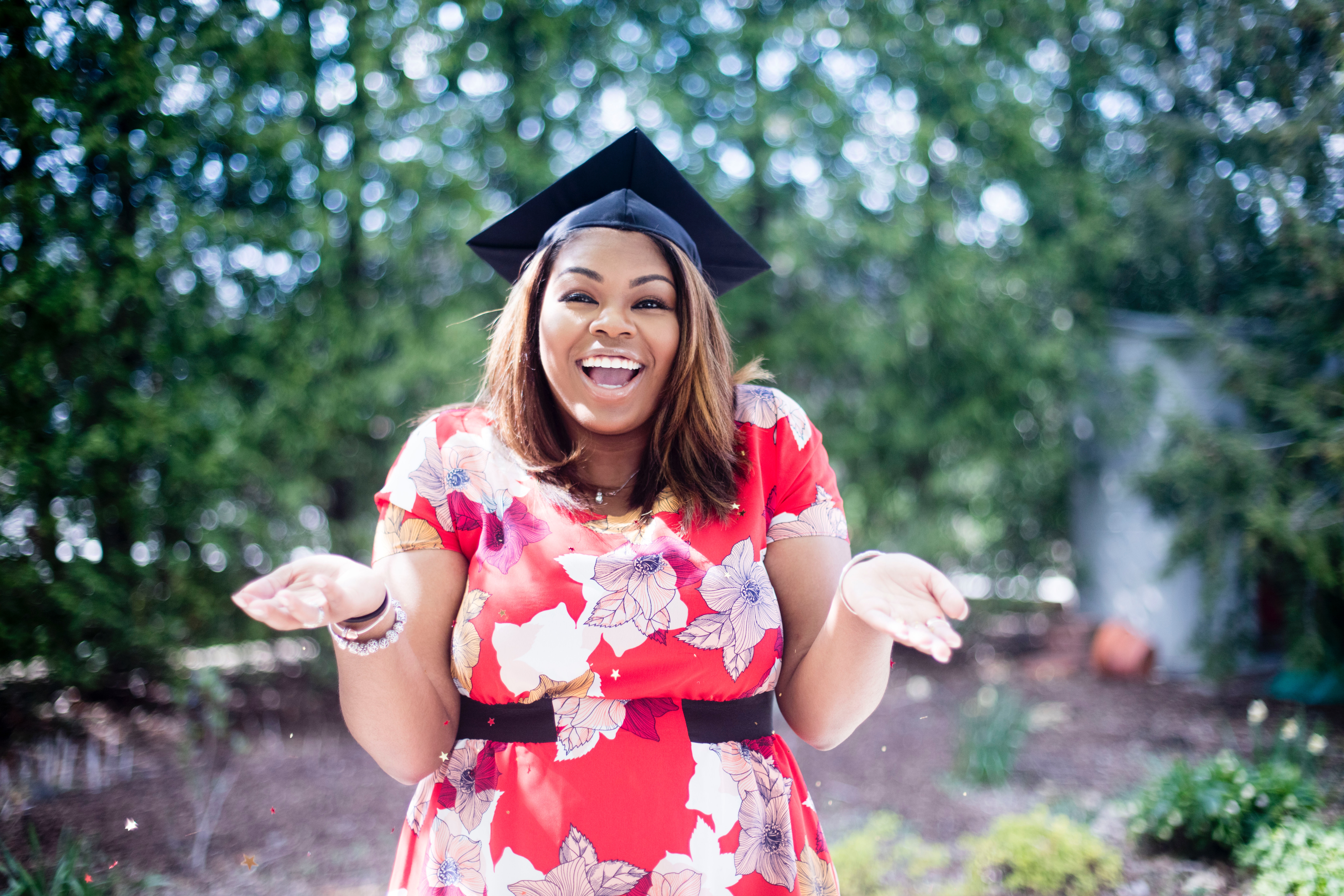 an image of a university graduate with her hands up 